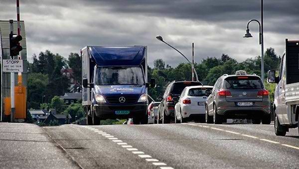 Blå Kurer lastebil kjører ned trafikkert vei